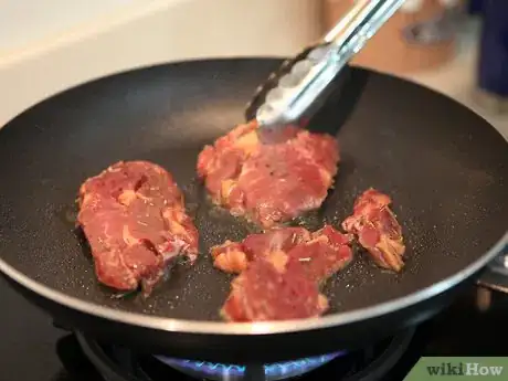 Step 6 用夹子夹住肉，煎比较肥的一侧，让油流到锅里。