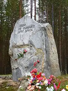 The monumental slab at the entrance to the Sandarmokh burial grounds reads: "People! do not kill one another", Russia