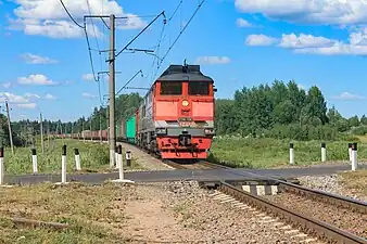 2TE116-1736 diesel locomotive with a freight train is passing level crossing near platform