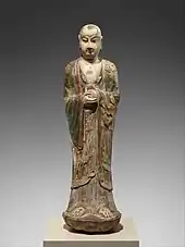 Colored limestone sculpture of monk holding an unidentified object