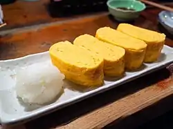 plate with two pieces of tamagoyaki, sliced crosswise to show spiral form