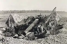 A gun assigned to the US Army in a revetment.  It has been jacked up and the bogies are being removed.