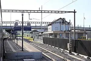 Two-story building with gabled roof next to double-track railway line with island platform