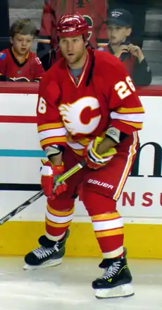 A player in a red uniform with yellow and white stripes at the waist looks into the distance.