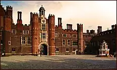 The courtyard of a red brick palace with tall chimneys and crenellations.