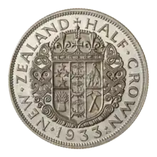 A coin featuring the Coat of Arms of New Zealand, surrounded by Maori wood carvings and the encircling text "NEW ZEALAND HALF CROWN 1933."