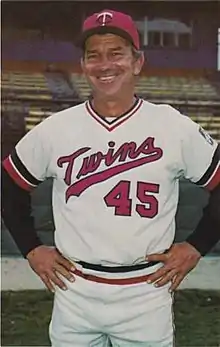 A man in a white baseball uniform and red cap