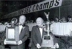 Two men holding trophies