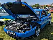 Front-three-quarter view of car with clamshell bonnet open, revealing the engine