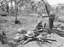 Soldiers armed with rifels and sub-machine guns occupy a defensive position during training