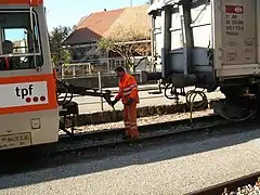 Meter gauge TPF BDe 4/4 123 is coupled to a standard gauge wagon on transporter trucks in Broc-Fabrique