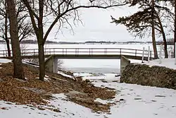 A footbridge parallel to the shore of an ice-covered lake