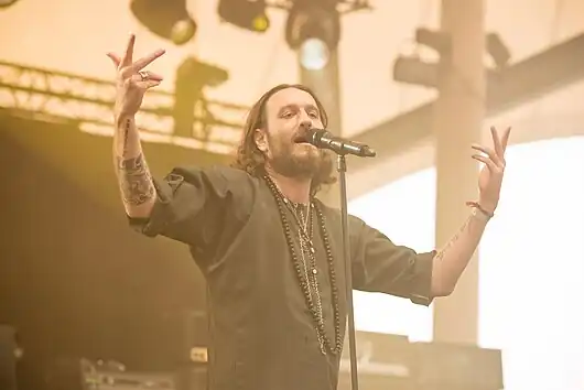 Kobi Farhi upclose, standing onstage, singing into a microphone