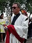 A priest carrying an arm reliquary