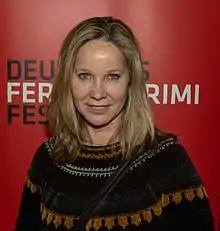 Ann-Kathrin Kramer wearing a dark patterned sweater, grinning directly at camera