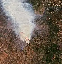 A satellite image shows the Oak Fire roughly in the center as a brown burned patch with an infrared glowing fire line on the northeast side and gray smoke pouring out to the north.