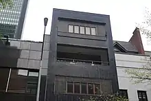 Detail of the facade on the upper stories, with glass blocks on the fifth story and a balcony below the fourth story