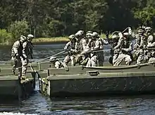 A group of soldiers in green fatigues assembling a bridge