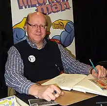 Simpson seated at a table smiling