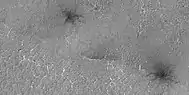 Close view of spider formations, as seen by HiRISE under HiWish program The polygon shapes are channels caused by pressurized carbon dioxide going through cracks.  During the winter season, a slab of dry ice forms on the ground surface.  The surface contains cracks in the shape of polygons.  During certain times, CO2 under the ice becomes pressurized from sunlight penetrating the slab of dry ice.  As the gas moves around the channels become larger.