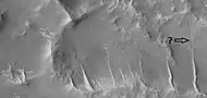 Close view of ridges and possible faults that are visible as straight lines, as seen by HiRISE under HiWish program Arrow points to a narrow trough that lines up with a ridge.