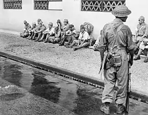 A soldier from the 5th Indian Division stands guard over Japanese prisoners