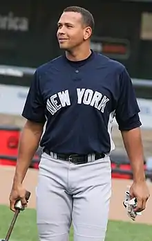 A man in a navy blue baseball jersey and gray pants