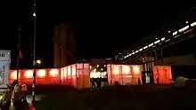 night time shot of silhouetted people milling about big glowing orange red fences