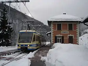 Two-story building with hip roof in snow, next to a side platform