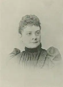 B&W portrait photo of a middle-aged woman wearing a high-collared dark shirt.