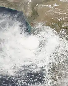 A satellite image shows a deep depression with a small central dense overcast, and moved towards the Gujarati coast.