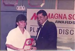 Two smiling men holding a record award