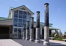 Five pillars lead to a building with a wall of windows.