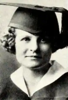 A young white woman with curly bobbed hair, wearing an academic cap and gown