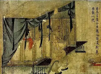 A woman seated inside a canopied bed, with a man sitting on the edge