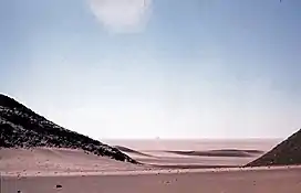 "Adrar Bous in the modern day."  A desert landscape with a bright blue sky.