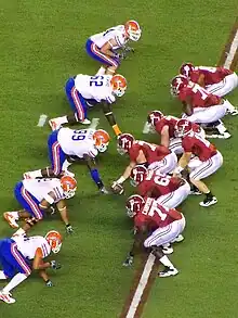 American football players on the line of scrimmage awaiting the snap.