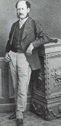 photo of a man standing and leaning against a piece of furniture