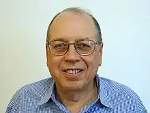 Shoulder high portrait of man in his sixties in a checked shirt with a blank white background