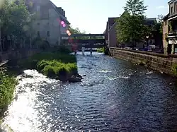 A river flowing through a town. In the background there is a bridge.