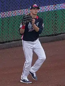 A man wearing a navy blue baseball jersey and white pants