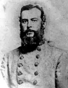 Black and white photo shows a heavily bearded man wearing a light gray military uniform with two rows of buttons