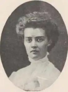 A young white woman with wavy hair in a bouffant style; she is wearing a high-collared white shirtwaist