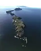 Aerial view of Anacapa with the lighthouse and coastguard station on East Anacapa in the foreground and Middle and West Anacapa behind. Santa Cruz Island is on the horizon.