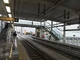 Multiple people wait at the platforms of a station.