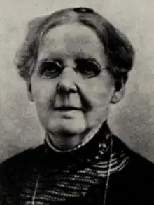 An older white woman wearing small oval glasses