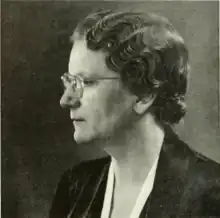 A woman with short hair and glasses, facing right of camera