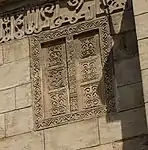 Carved image of doors, on left side of the façade