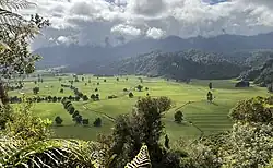 view up a valley with green fields, trees, and hills