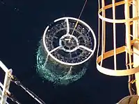 A CTD-rosette comes up out of the water just before it gets recovered and brought on deck of the ship.